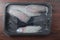 Fresh raw monk fish fillet on a black plastic tray in vacuumed package for freshness on a wooden table. Retail industry product.