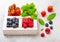 Fresh raw organic berries in white vintage wooden box on kitchen table background. Top view. Strawberry, Raspberry, Blueberry and