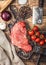 Fresh raw organic slice of braising steak fillet on chopping board with meat hatchet on wooden background. Red onion, tomatoes