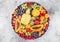 Fresh raw organic summer berries and exotic fruits in round large tray on light kitchen background. Papaya, grapes, nectarine,