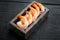 Fresh raw peeled king prawn shrimps with tail, in wooden box, on black wooden table background