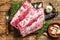 Fresh raw pork rack spareribs with thyme and garlic on cutting board. wooden background. Top view