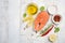 Fresh raw salmon steak with lemon, olive oil and spices on rustic wooden background. Ingredients for making healthy dinner. Health