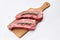 Fresh raw striploin steak on wooden board on white background with rosmary top view