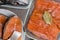 Fresh raw trout or salmon fish slices steak in white plate, head, fillet in glass bowl, with spices on stone background. Creative