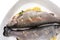 Fresh, raw two trout lying on a plate, stuffed with butter, parsley and lemon slices, isolated on a white background with a clippi