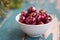 Fresh red cherries in a bowl, outdoors on a garden table