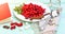 Fresh red cornel berries on white plate, preparing for homemade cornelian cherry jam, surrounded by jelly jar.