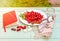 Fresh red cornel berries on white plate, preparing for homemade cornelian cherry jam, surrounded by jelly jar.