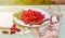 Fresh red cornel berries on white plate, preparing for homemade cornelian cherry jam, surrounded by jelly jar.