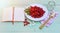 Fresh red cornel berries on white plate, preparing for homemade cornelian cherry jam, surrounded by jelly jar.