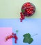 Fresh red currants in tiny metal vintage basket on geometric  pink, green and blue craft paper background top view