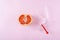 Fresh red cut grapefruit and gynecologic speculum on pink background. Female gynecological health concept. Fruit as symbol of