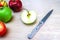 Fresh, red, green and yellow red apples, in the center is a cut apple and knife