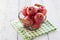 Fresh red juicy apples in a basket on a green textile on a wooden background