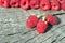 Fresh red natural raspberries branch and rows behind on cracked wooden background