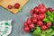 Fresh red radishes on grey background, wooden board and dish towel.