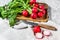 Fresh red radishes in a wooden bowl. Farm organic vegetables. Gray background. Top view