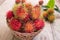 Fresh red rambutan sweet delicious fruit in basket on wood table. Tropical fruit tree, native to South - East Asia , cultivated in