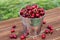 Fresh red ripe cherry in a bucket on the wooden background. Ripe red cherries in the metal bucket on a wooden background