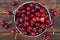 Fresh red ripe cherry in a bucket on the wooden background, top view. Ripe red cherries in the metal bucket on a wooden background