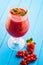 Fresh red smoothie with mint leaf in glass on blue background, strawberry, red currant or beetroot fruit drink, product
