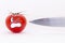 Fresh red tomato with scared face and sharp knife blade