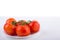 Fresh red tomatoes on a white plate at a white table shot from the front