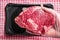 Fresh rib eye steak in butcher hand second steak on a black plastic tray. Meat industry product. Premium top quality cut of beef.