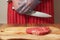 Fresh rib eye steak on a wooden board. Professional butcher in red apron