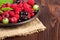 Fresh ripe berries in the bowl on the old wooden table. Useful natural food.