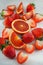 Fresh ripe blood oranges and strawberries, slices, rustic food photography on white wood plate