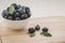 Fresh ripe blueberries with leaves in bowl on wooden tray/Fresh ripe blueberries with leaves in bowl on wooden tray. Copy space.