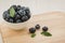 Fresh ripe blueberries with leaves in bowl on wooden tray/Fresh ripe blueberries with leaves in bowl on wooden tray. selective