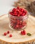 Fresh ripe cranberries in a transparent glass jar on a wooden stand. Autumn, useful berries. Harvest