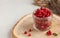 Fresh ripe cranberries in a transparent glass jar on a wooden stand. Autumn, useful berries. Harvest. Copy space