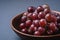 Fresh ripe grape berries in brown wooden bowl on blue grey minimal background
