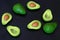 Fresh ripe green avocado fruits, whole and cut in half, on black