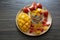 Fresh ripe mango and strawberry fruit in a cup with cookies, and soy yogurt on a wooden plate