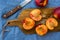 Fresh ripe nectarines, halved, whole on wood cutting board, knife, on blue table cloth, top view, close up, vibrant colors