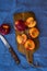 Fresh ripe nectarines, halved, whole on wood cutting board, knife, on blue table cloth, top view, flat lay, close up, vibrant colo