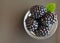 Fresh ripe organic blackberries in a glass bowl on a grey background.Blackberry.Healthy food or diet concept.