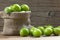 Fresh ripe organic green plums or greengage in burlap sack on wooden background