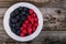 Fresh ripe organic raspberries and blackberries in a bowl on a wooden background