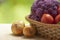 Fresh ripe purple cauliflower, onion, red tomatoes and green cucumber in basket. Healthy food on table on defocus autumn
