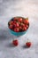 Fresh ripe strawberry fruits in blue bowl, summer vitamin berries on grey stone background