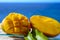 Fresh ripe sweet yellow mango fruit served on glass plate with blue seaview background