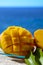 Fresh ripe sweet yellow mango fruit served on glass plate with blue seaview background