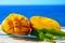 Fresh ripe sweet yellow mango fruit served on glass plate with blue seaview background