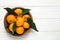 Fresh ripe tangerines with leaves and space for text on wooden table, top view. Citrus fruit